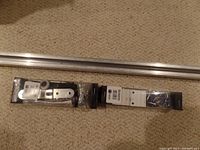 Sliding closet door ceiling mount rail laid out on carpet with hardware packages near one end.