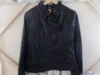 Front view of black women's leather jacket showing asymmetrical zipper, stitched panels, and side pockets.