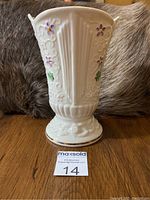 Front view of white porcelain vase with shamrocks and purple flowers, showing detailed piercing and embossed floral pattern.