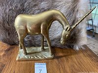 Side profile of the brass antelope showing body and base details with a fur backdrop.
