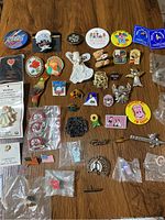 Wide layout image of assorted buttons, pins, and brooches displayed on a wooden table showing varied colors and shapes.
