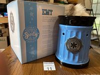 Photo of the blue ceramic Scentsy EMT warmer next to its original box showing branding and product name