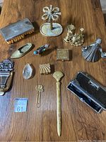 Overview of metal and brass decorative items laid out on wooden surface.