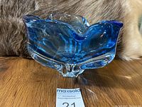 Side view showing the heavy, thick glass with blue coloration and organic scalloped edges.