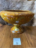 Side view of Haeger Pottery footed bowl showing mottled yellow-brown glaze and Haeger label on base.