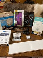 Full lot view showing Otterbox PopSocket case, OloClip lens, Smart Wi-Fi plug, Belkin headphone splitter, iWatch band, Road ID Fitbit badges, MyID emergency ID bracelet, and car reading light.