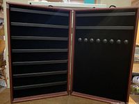 Photo showing right side of wooden folding jewelry case featuring multiple round knobs for hanging necklaces or jewelry.