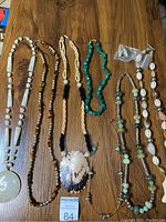 Full view of seven vintage necklaces displayed on a wood surface, showing materials and styles.