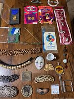 Top down photo of vintage hair accessories, awards, pins, Disney luggage tag, and other miscellaneous items laid out on wooden surface.
