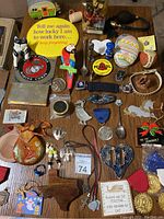 Top down view of varied small items spread out on a table including figurines, cookie cutters, keys, pins, and small plaques