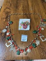 Full view of the necklace laid flat on a wooden surface showing all charms including cactus, chili peppers, stars, and animals.