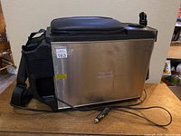 Full side view of the stainless steel travel cooler and warmer with attached power cord and shoulder strap.
