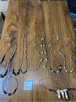 Top view of eight sterling silver necklaces with various beads and stones displayed on a wooden surface.