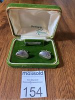 Full set of cufflinks and tie clip in original green velvet-lined box with satin interior lid displaying 'Sterling by Raimond'