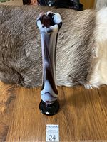 Front view of 10.5 inch tall purple and white swirled slag glass swung vase on a dark table with animal hide background.