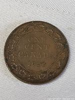 Close-up of one side of the 1920 Canadian large one cent penny coin showing the denomination, country and date within a maple leaf wreath.