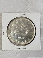 Photo of 1937 Canada Silver Dollar coin showing detailed inscription and canoe design.