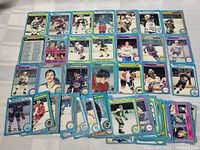 Spread of approximately 33 different 1979-80 OPC hockey cards arranged on a surface showing front views of players with team colors, blue borders, and player information.