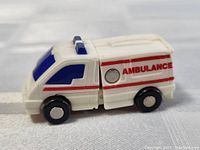 Front and side view of the white Transformer ambulance toy with red stripes and blue windows