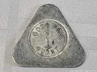 Front view of triangular metal token with centered round emblem reading "GOOD FOR 1 QUART"
