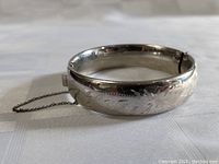 Front view of antique sterling silver bracelet showing thick band and carved floral details.