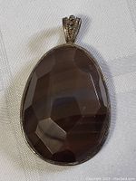 Front view of large faceted agate jasper stone with dark hues and intricate metal frame with bail.