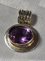 Full view of pendant showing amethyst and silver setting with decorative bail.