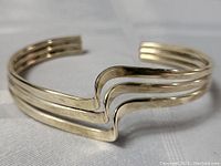 Image showing front and side angle of sterling silver cuff bracelet highlighting the three parallel bands with a distinctive wave detail in the center.
