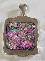 Front view of the large pendant showing the sterling silver frame and colorful textured glass inlay with dominant purple hues and iridescent colors