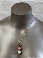 Full view of necklace on mannequin showing the 18 inch sterling silver chain and trio pendant with red, pink, and cream stones.