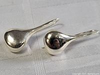 Top view of the polished sterling silver teardrop-shaped earrings, showing smooth reflective surface and curved shape.