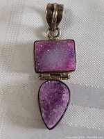 Close-up image of sterling silver pendant showing rectangular and teardrop-shaped raw amethyst stones with crystalline texture and purple color variations.