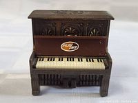 Front view of the mini piano pencil sharpener showing keyboard and decorative paneling with PLAYME sticker on lid