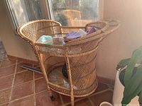 Front angle view of bar cart showing wicker frame, glass top, handles and lower shelf