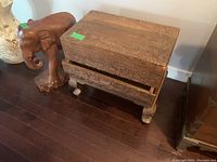 Wood carved chest with decorative carvings and wood carved elephant beside it on wooden floor