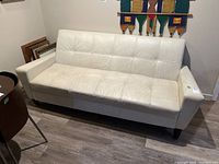 Full front view of white leather couch showing stitching details and overall shape.