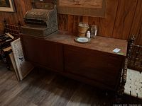 Front view of walnut veneer sideboard with cash register, plate and jars on top.