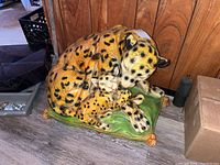 Front view of composite leopard and cub statue on green cushion