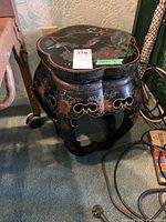 Side view of the black lacquered Asian style side table with painted floral and bird motifs and carved decorative apron.