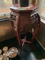 Front angle showing detailed carved floral legs and octagonal stone insert on table top.