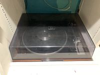 Front view of the Sansui SR-1050C turntable with closed dust cover showing the unit resting on a white shelf.