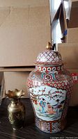 Photo showing both the large ceramic urn with lid and the smaller brass metal vase side by side