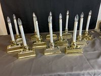 Overall view of all 12 electric window candles lit and displayed on a table with black backdrop.