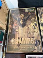 Framed Boston Herald front page 'CHAMPS!' showing Patriots player raising arms, headline about 20-17 Super Bowl win vs Rams.