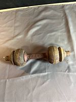 Full view of antique Weider dumbbell showing round cast iron weights at each end and straight handle with visible rust.