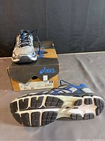 Front and sole view of one ASICS GT-2110 shoe with original box in background, showing tread detail and color scheme.