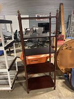 Full view of dark wood shelving unit with four shelves and ornate metal caps on posts