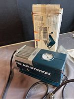 Photo showing the Black & Decker Air Station portable air compressor with original box in the background and attached power cord and hose.