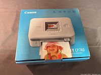 Canon Selphy CP740 photo printer box front showing printer image and printed photo.