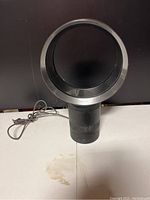 Front view of black Dyson Cool AM06 bladeless desk fan showing circular loop and base with attached power cord.